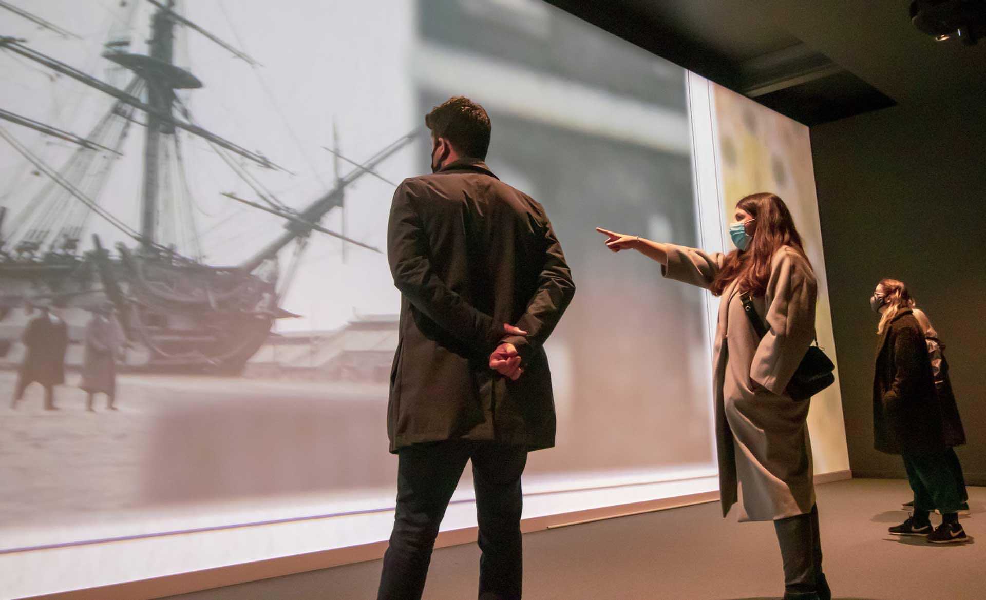 A man and a woman watch the immersive video experience in the Victory Gallery at Portsmouth Historic Dockyard